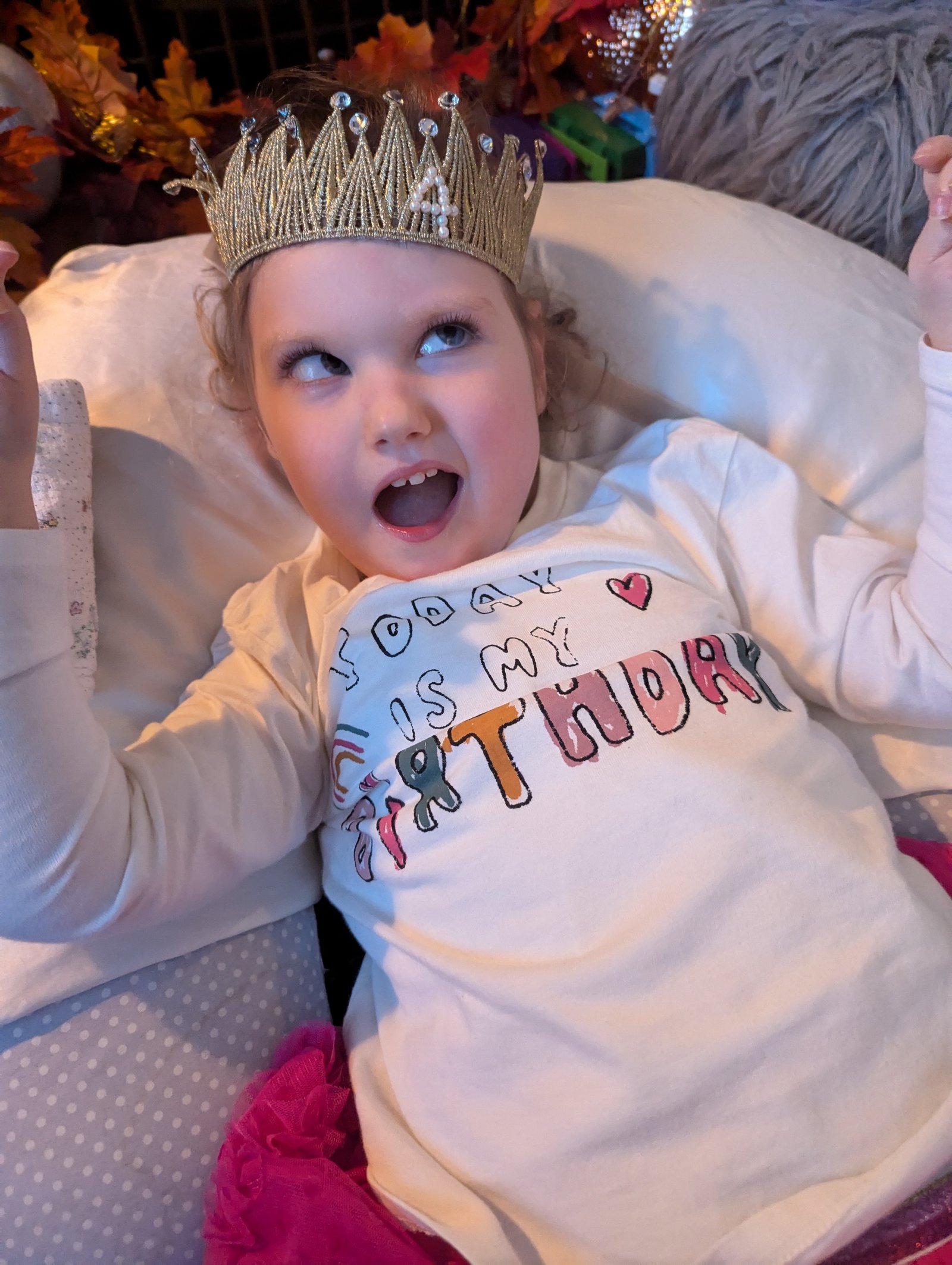 Grace on her birthday wearing a crown, arms outstretched