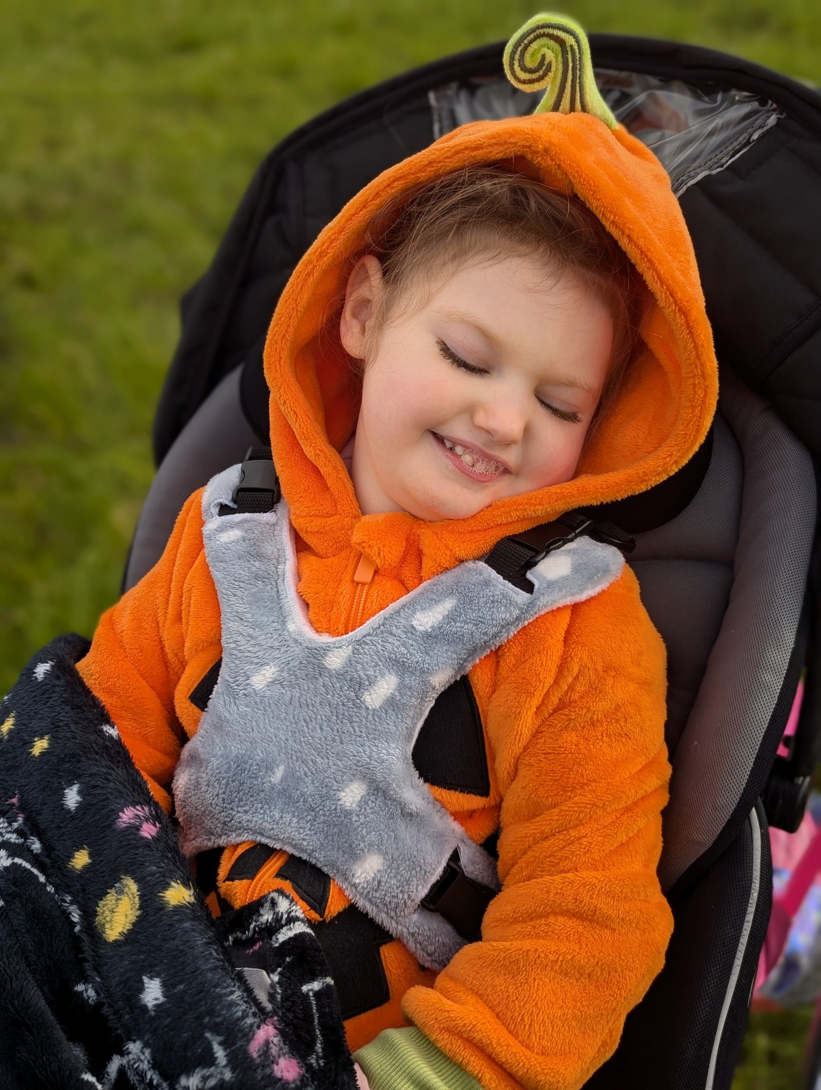 Grace in her pumpkin onesie, smiling with eyes closed